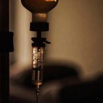 Close-up of IV drip chamber in low light, symbolising recovery, hydration, and athletic performance support.